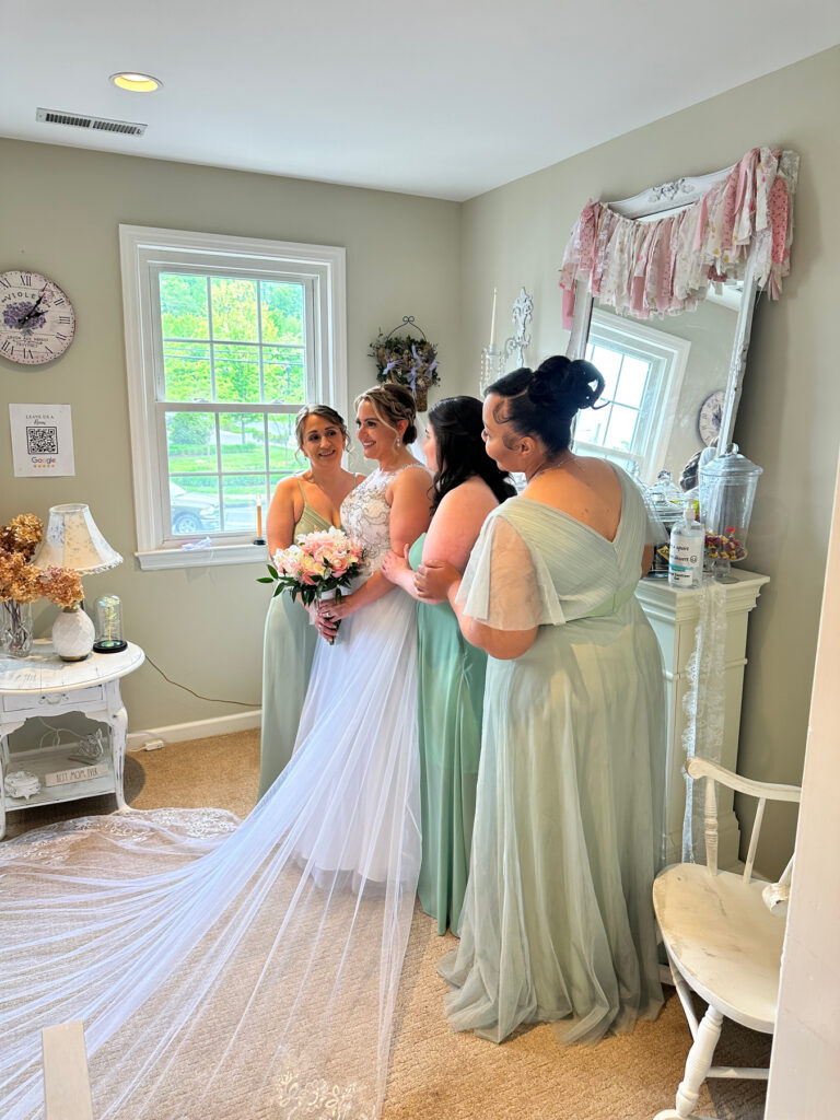 Bride and bridesmaids posing for photos in a shabby chic bridal loft in Monroe, CT, wearing their dresses before the wedding ceremony.