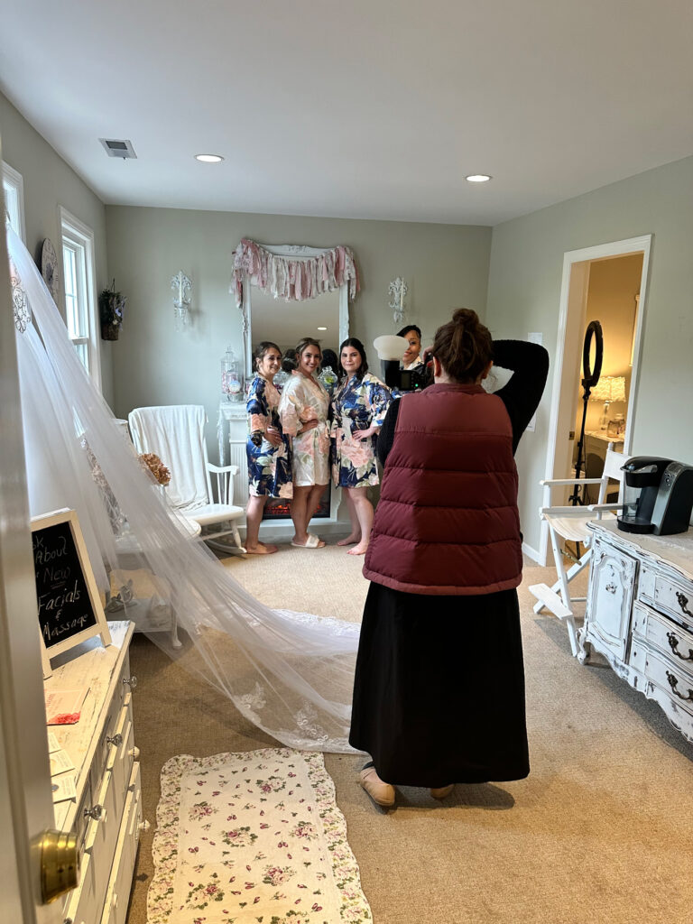 Bride and bridesmaids posing for photos in a shabby chic bridal loft in Monroe, CT, wearing floral robes before the wedding ceremony.
