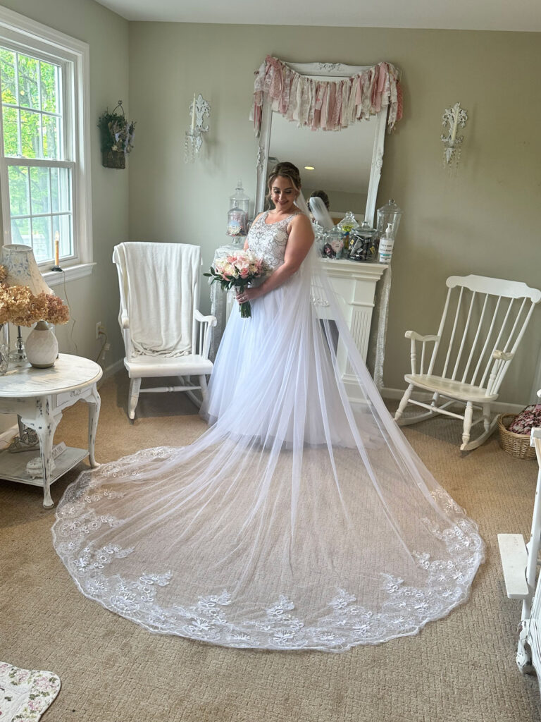 Bride posing in her wedding gown with a long train and bouquet in a vintage-inspired bridal loft in Monroe, Connecticut.