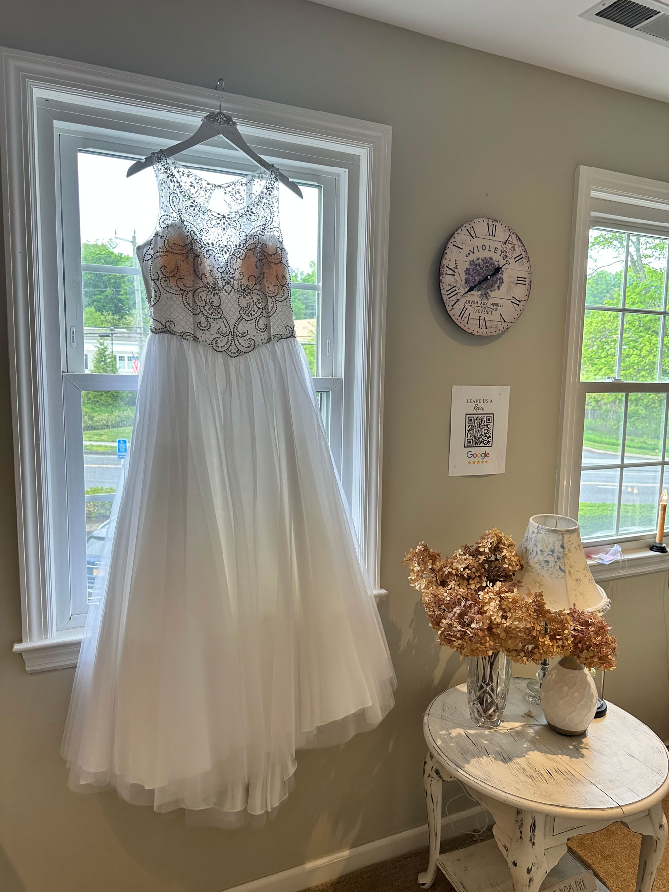 Brides dress hangingin window morning of wedding in a vintage-inspired bridal loft in Monroe, Connecticut.