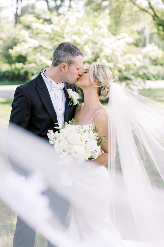 Bride and groom sharing a romantic kiss outdoors after their Fairfield County wedding, featuring flawless hair and makeup by A Touch of Color.