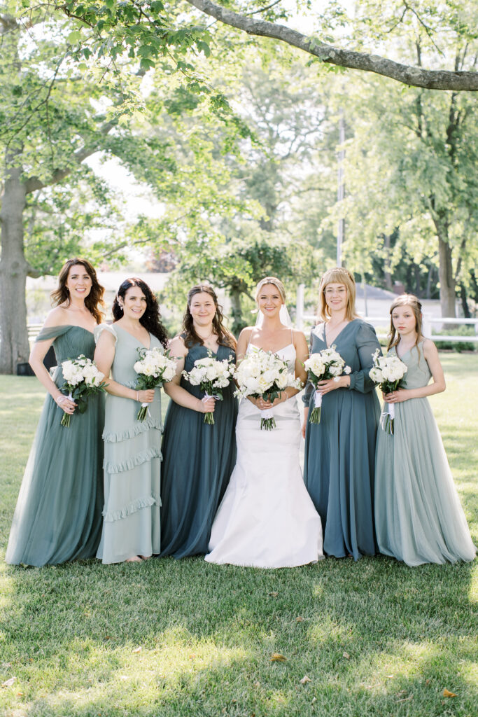 Bride surrounded by bridesmaids outdoors in Fairfield County, CT, all styled by A Touch of Color Makeup and Hair for a cohesive, elegant bridal look.